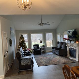 A cozy living room decorated for the holidays with a Christmas tree, fireplace, and comfortable seating.