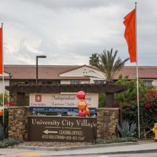 Entrance sign of University City Village adorned with balloons and flags.