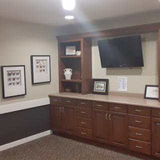 A modern office space featuring wooden cabinets, a television, and framed photographs on the wall.