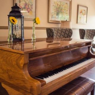 A wooden piano adorned with a decorative lantern and surrounded by framed paintings.