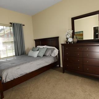 A neatly arranged bedroom with a bed and dresser.