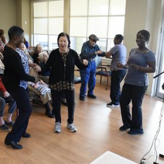 Seniors engaging in a joyful dance activity, promoting social interaction and movement.