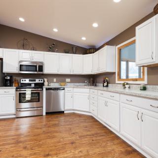 A modern kitchen featuring sleek white cabinets and stainless steel appliances, illuminated by natural light.