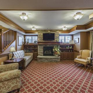 A cozy living room featuring a stone fireplace, patterned carpet, and comfortable seating.