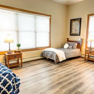 A cozy bedroom with twin beds and natural light streaming through the windows.