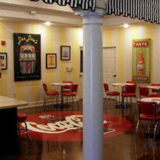 A vintage-style diner interior with Coca-Cola themed decor and red chairs.