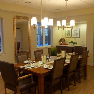 A warm and inviting dining room with a large table set for a meal, surrounded by comfortable chairs and illuminated by overhead lighting.