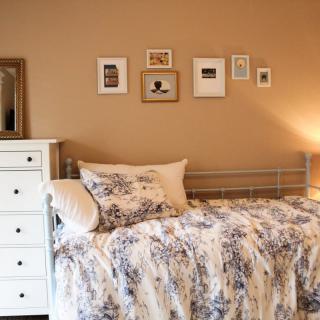Cozy bedroom with floral bedding and wall art.