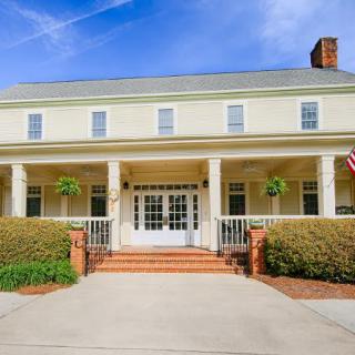 A colonial-style house with a large front porch and paved driveway.