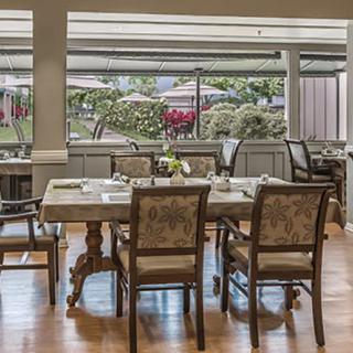 A well-appointed dining room with elegantly set tables and chairs, providing a pleasant window view of the outdoors.