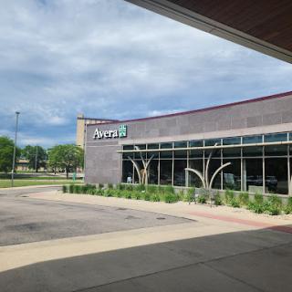 A modern commercial building with unique architectural features and greenery surrounding the entrance.