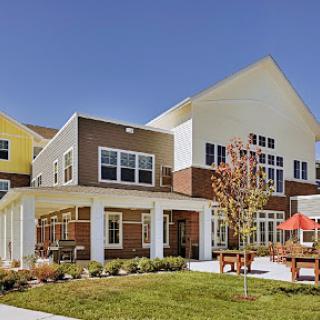 A modern residential building featuring a blend of colors and outdoor seating.