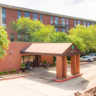 A brick hotel entrance with a covered walkway surrounded by greenery.