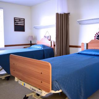 A serene hospital room featuring two adjustable beds with blue bedding, designed for patient comfort.