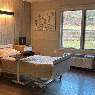 A modern hospital patient room with a comfortable bed, natural light from the window, and minimalistic decor.