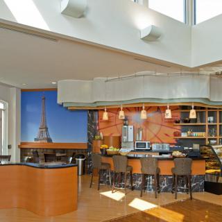 A modern kitchen with an open layout featuring a large Eiffel Tower mural, bar seating, and contemporary lighting.
