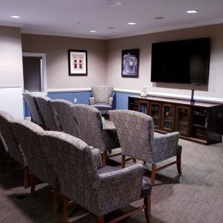 A cozy home theater setup with multiple rows of comfortable chairs facing a large television.