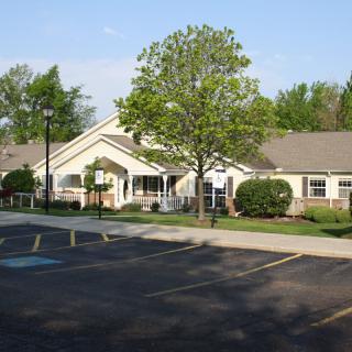 A suburban building with a parking lot and trees during the day.