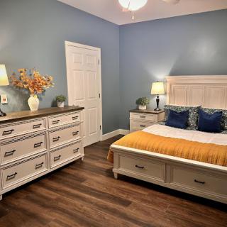 A cozy and stylish bedroom featuring blue walls, white furniture, and warm yellow accents.