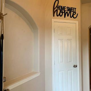 Home hallway featuring a white door and decorative 'Home Sweet Home' wall art.