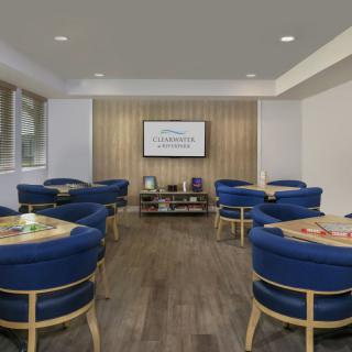 A modern lounge with blue chairs and a television on a wooden accent wall.