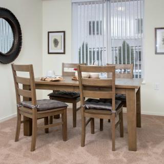 A cozy dining room with a wooden table and chairs, accented by decorative elements like wall art and a mirror.
