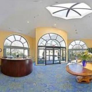 A spacious lobby area with large arched windows, a skylight, and elegant furniture.