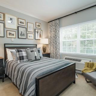 A stylishly decorated bedroom with striped bedding and a gallery wall of framed pictures.