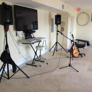 An indoor music setup featuring speakers, a guitar, microphone stands, and a television.