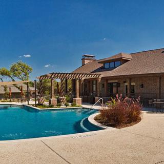 A luxurious house with a swimming pool and patio area under a clear blue sky.