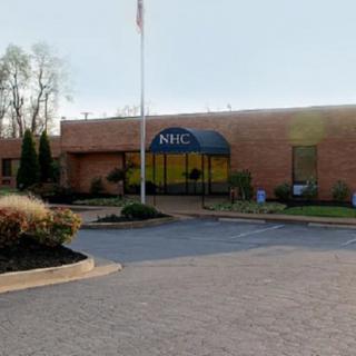 The exterior of an office building with an awning and parking area.