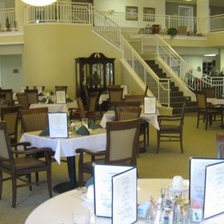 Elegant dining area with neatly arranged tables and a grand staircase.