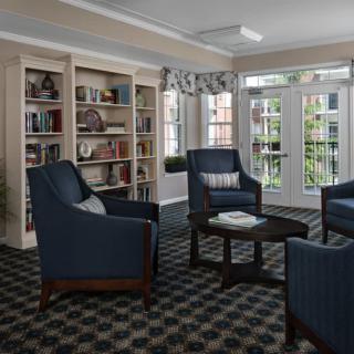 A cozy living room with blue armchairs and bookshelves by the window.