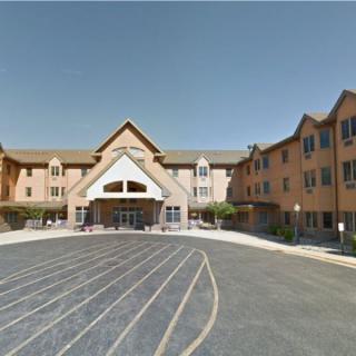 A large building with a prominent entrance and a parking lot in front.