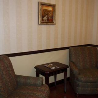 A cozy living room setup with two chairs, a small wooden table, and a painting on the wall.