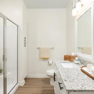 Modern bathroom with glass shower and granite countertop.