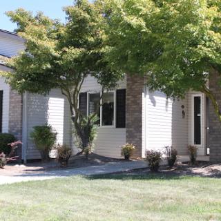 A beautiful residential home featuring a well-maintained lawn and surrounding trees.
