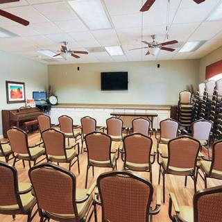 An empty conference room with rows of chairs and a television mounted on the wall.