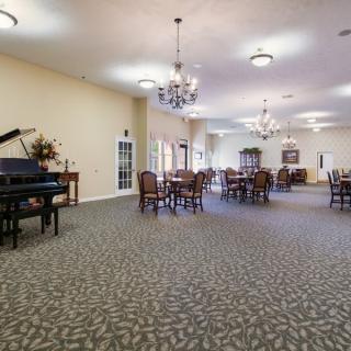 A spacious dining room with a grand piano and elegant chandeliers.