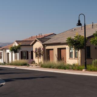 A suburban street lined with similar style houses under a clear blue sky.