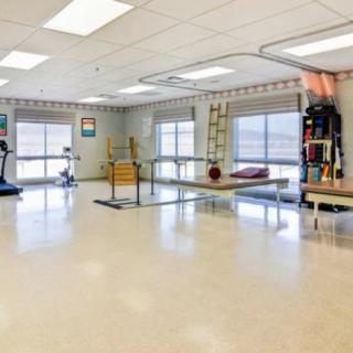 A spacious rehabilitation room equipped with various exercise and therapy equipment.