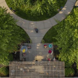 Aerial view of a landscaped area with people walking on a curved pathway surrounded by greenery.