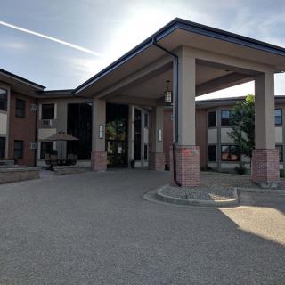 A modern building with a prominent entrance and columns under a clear sky.