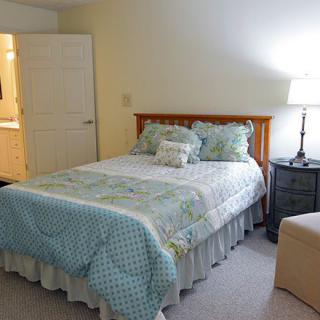 A cozy bedroom with a bed, nightstand, and lamp.