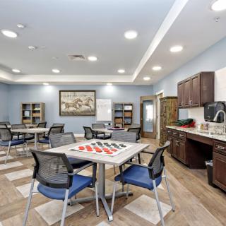 A modern meeting room with tables, chairs, bookshelves, and a coffee station.