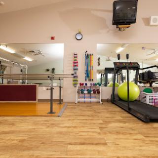 A well-equipped gym featuring a treadmill, exercise balls, and ample training space.