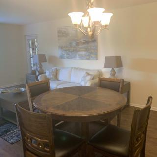 A cozy dining area with a round table, chairs, and a nearby sofa under soft lighting.
