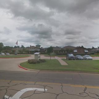 A view of a parking lot with buildings in the background on a cloudy day.