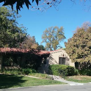A charming house surrounded by lush greenery and a clear blue sky.