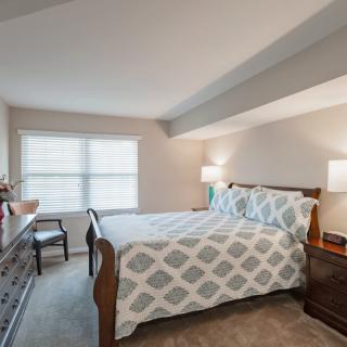 A cozy bedroom with a stylish bed, two lamps, and a large window letting in natural light.